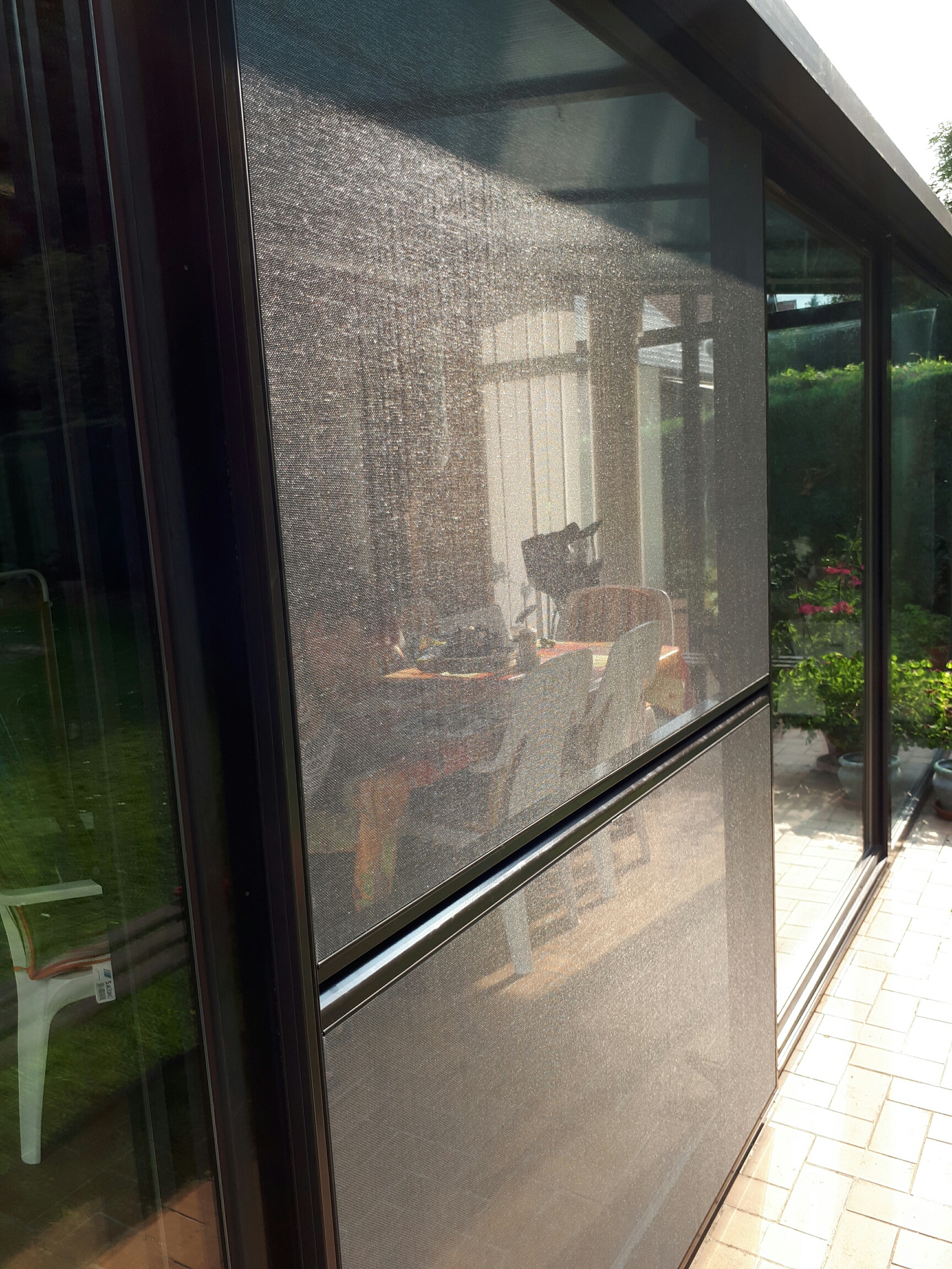 Moustiquaire coulissant Elegance plac&eacute;  sur les portes coulissantes d'une veranda.
La veranda est ainsi a&eacute;r&eacute;e avec un confort optimum car les insectes n'entrent pas dans la pi&egrave;ce. 